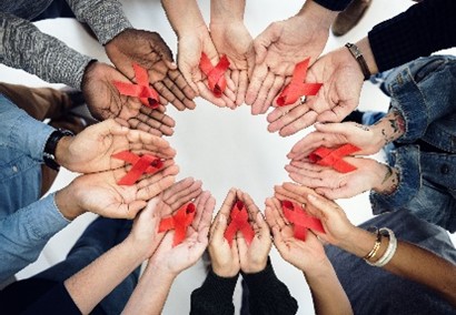 circle of hands holding red ribbons